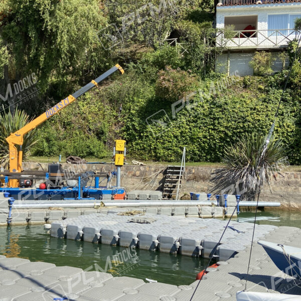 Grúa flotante color naranja sobre muelle