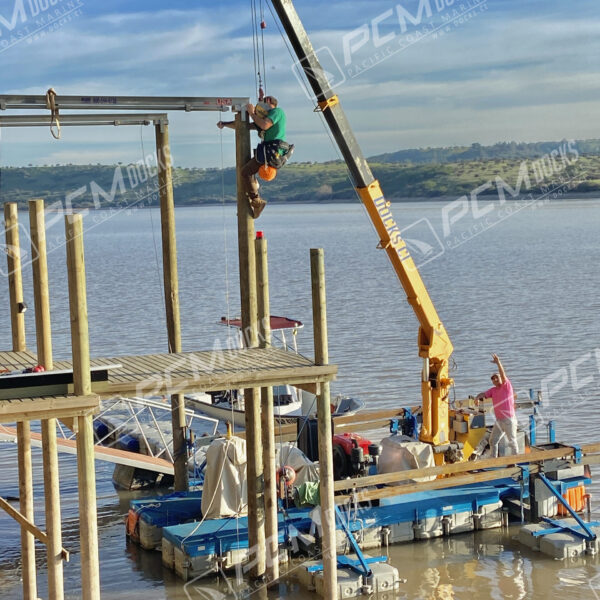Grúa de construcción naranja sobre muelle flotante